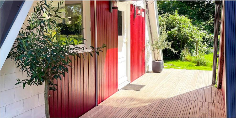 une porte rouge sur une maison avec une plante en pot dans l'établissement Chalet en Normandie au coeur du pays d'Auge, au Pin