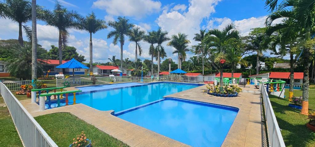 una piscina en un complejo con palmeras en Cabañas Cafeteras Cerritos, en Pereira