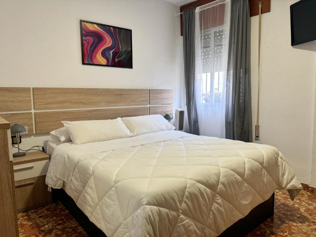 Un dormitorio con una gran cama blanca y una ventana en Apartamento San Agustín - Alojamientos El Duque, en Córdoba