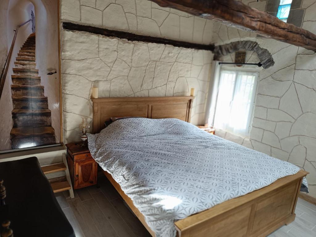 1 dormitorio con cama y pared de piedra en La petite tanière, en Fontan