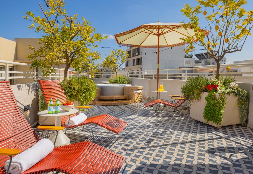 un patio al aire libre con sillas naranjas y sombrilla en Albi Florentin, en Tel Aviv