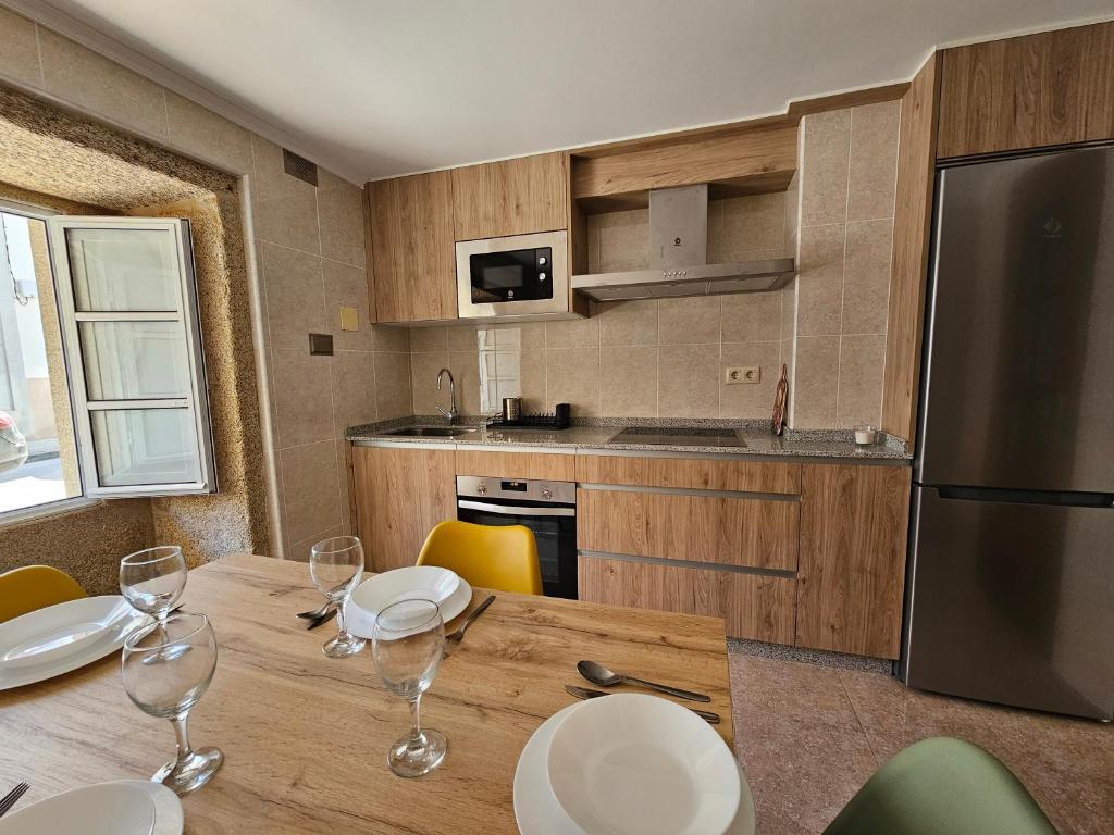 cocina con mesa de madera y copas de vino en Carmen House, en Laxe