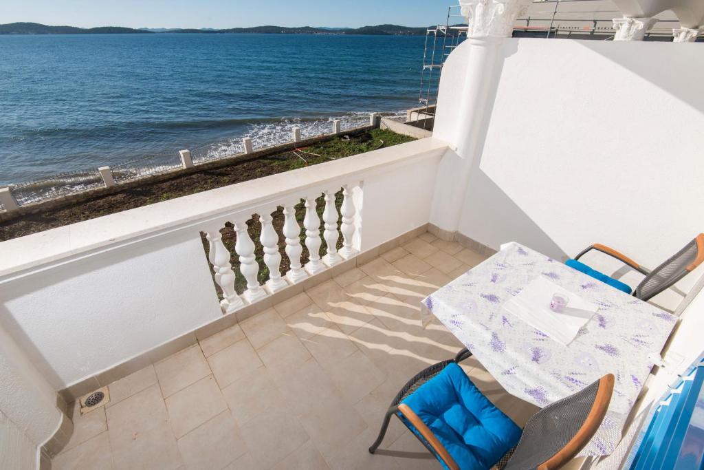 a balcony with a table and chairs and the ocean at Vila Niko Dalmacija in Sukošan