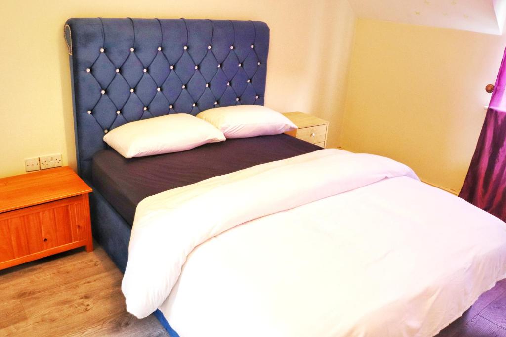 Bett mit blauem Kopfteil in einem Schlafzimmer in der Unterkunft Deluxe Dwelling - 15 mins from Cork City/Airport in Cork
