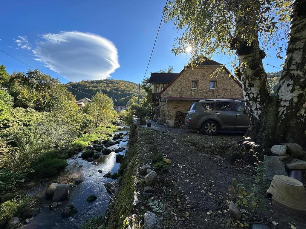 a car parked in front of a house next to a river at Izeria 112 Riverside House in Piechowice