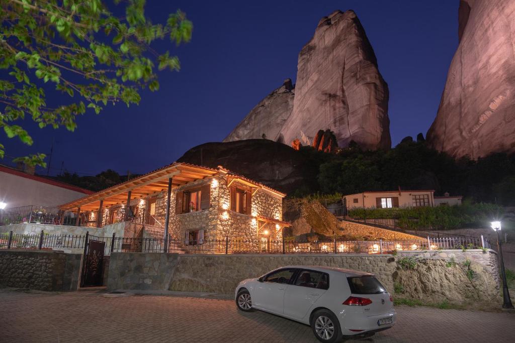 a white car parked in front of a building with a mountain at Voulas Traditional House Meteora 1 in Kalabaka