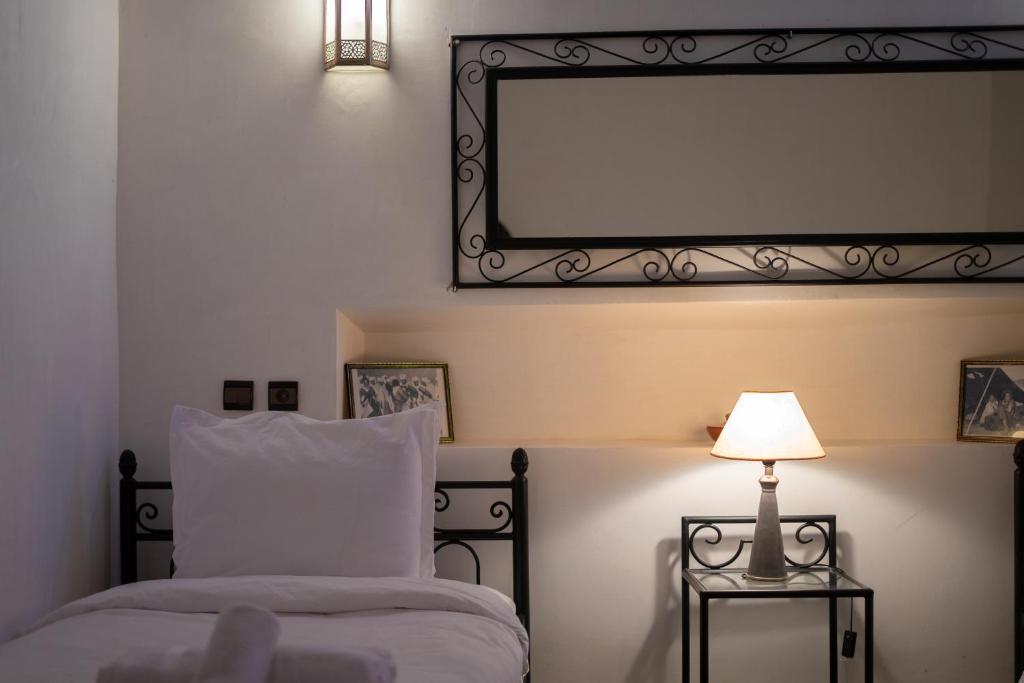 a bedroom with a bed with a mirror and a lamp at Dar Ait Bouguemez in Azilal