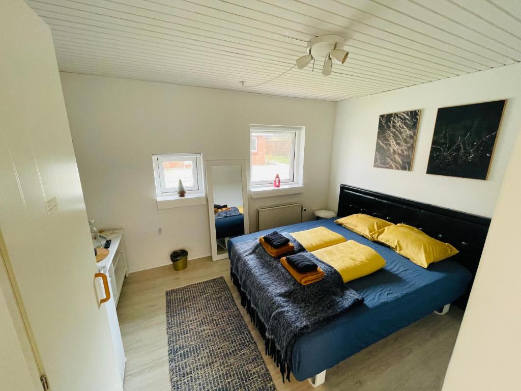 sypialnia z dużym niebieskim łóżkiem z żółtymi poduszkami w obiekcie 1 private room in Billund w Billund