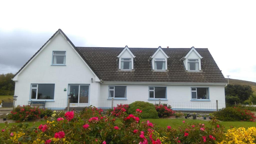 a white house with flowers in front of it at Achill Isle House in Keel