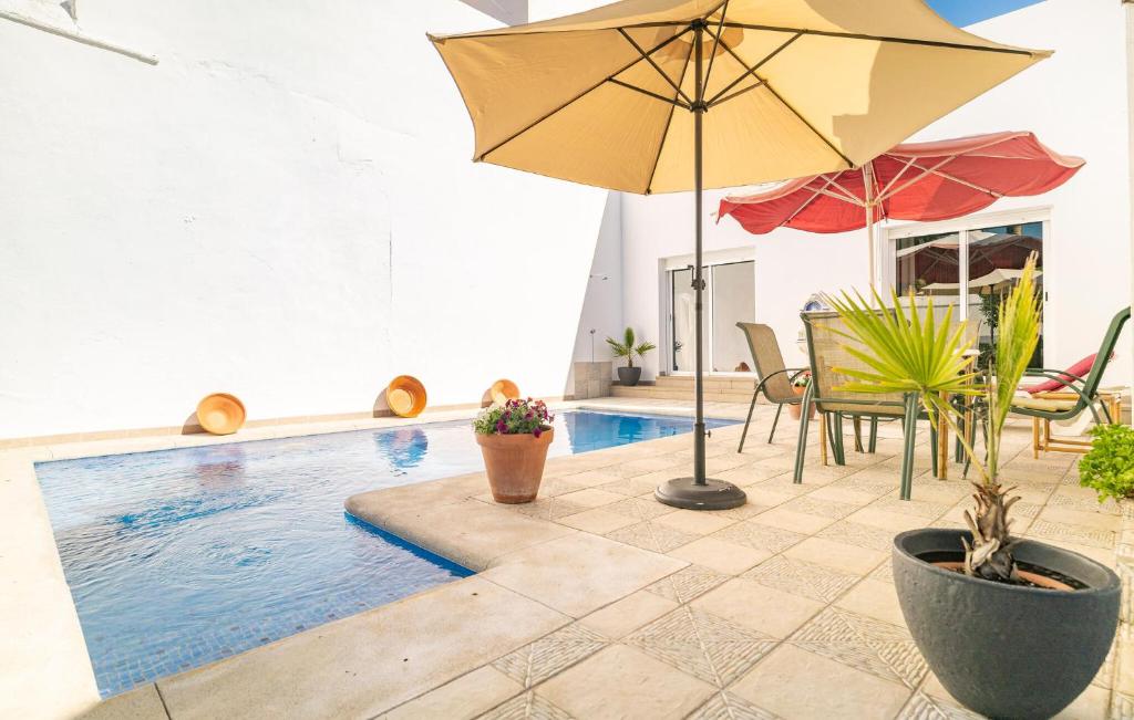 Peñaflor的住宿－La Casa Del Limonero，一个带遮阳伞和椅子及桌子的游泳池