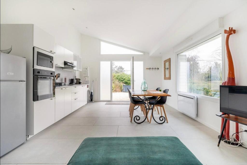 uma cozinha com electrodomésticos brancos e uma mesa com um tapete verde em Villa entourée de verdure avec parking privé em Halluin