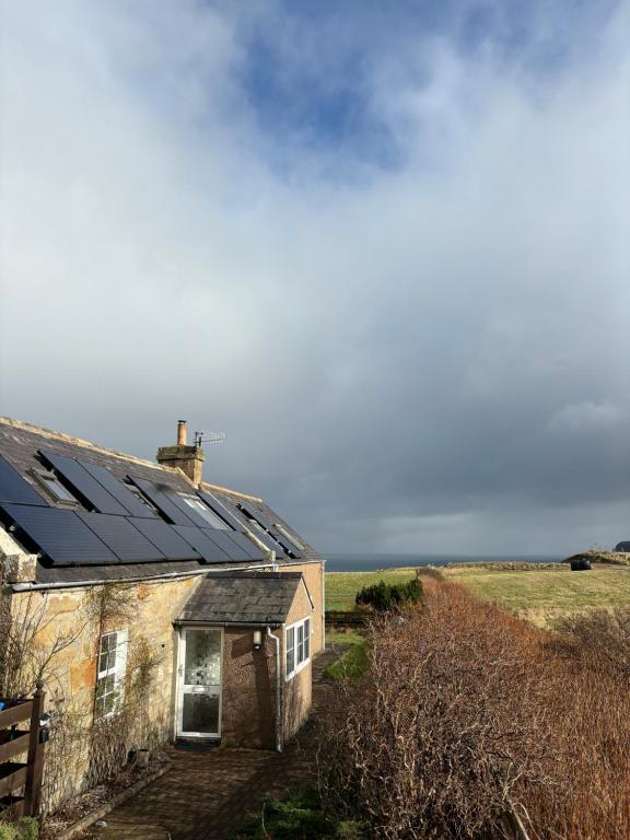 an old house with solar panels on the roof at Traditional 2 bed croft in Portskerra