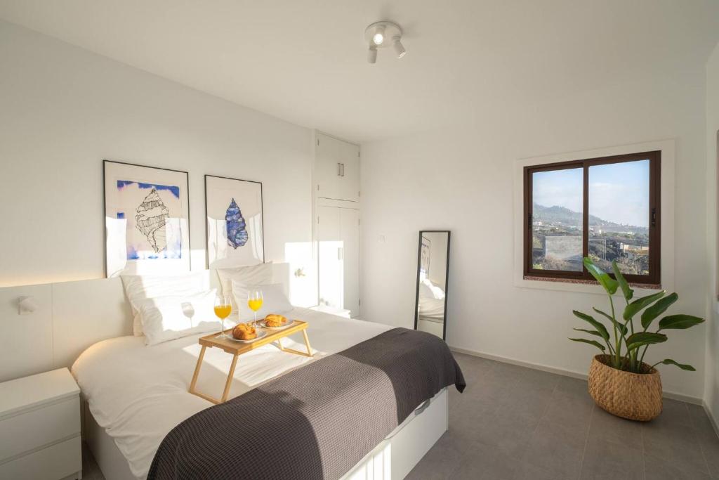 Un dormitorio con una cama y una mesa con bebidas. en Finca Las Huellas - Moderno apartamento con vistas al mar y al volcán, en Los Llanos de Aridane