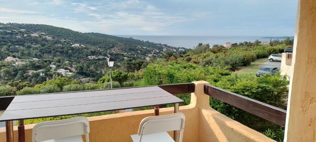 un balcon avec une table de pique-nique et deux chaises dans l'établissement Haut de Mazet vue mer et piscine partagée, à Roquebrune-sur Argens