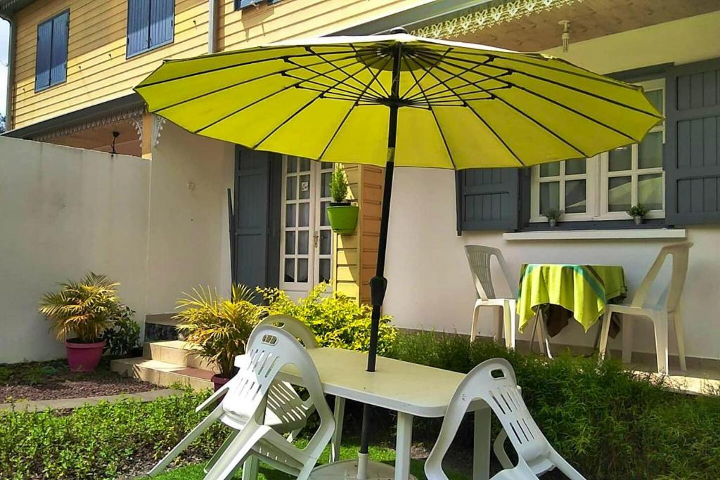 una mesa con sombrilla amarilla y 2 sillas en Maison de 2 chambres avec terrasse et wifi a Hell Bourg, en Hell-Bourg