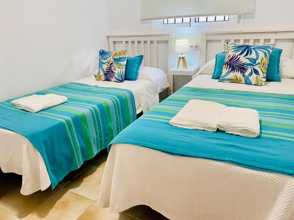 2 camas con sábanas azules y blancas en una habitación en Apartamentos Rubio, en Chipiona