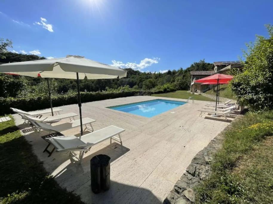 BistagnoにあるVilla La Ginestra Piemonte with private poolの椅子2脚と傘が備わったプール
