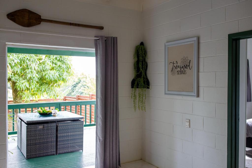 Zimmer mit einer Tür, die auf einen Balkon mit einem Tisch führt. in der Unterkunft Joseph Retreat in Avarua