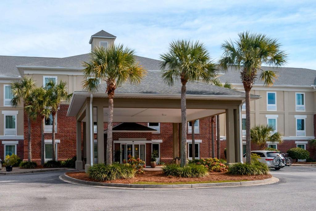 a hotel with palm trees in front of a building at Comfort Inn & Suites Patriots Point in Charleston