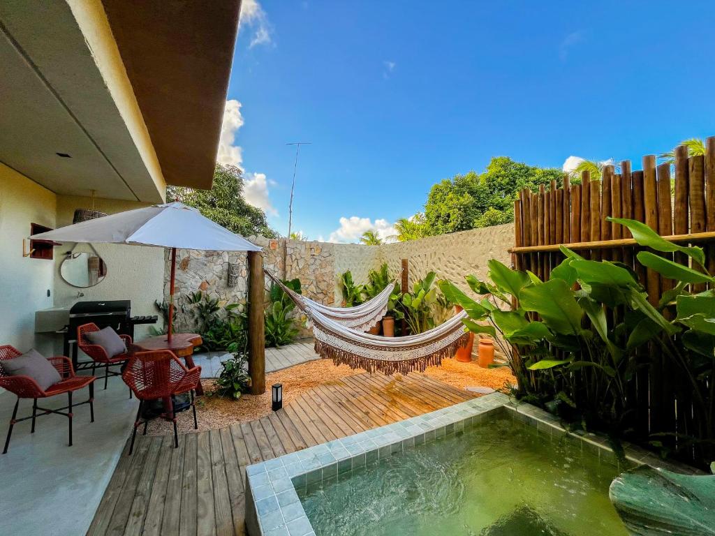 une cour avec un hamac et une piscine dans l'établissement Villa Aconchego - Casas de Luxo, à São Miguel dos Milagres