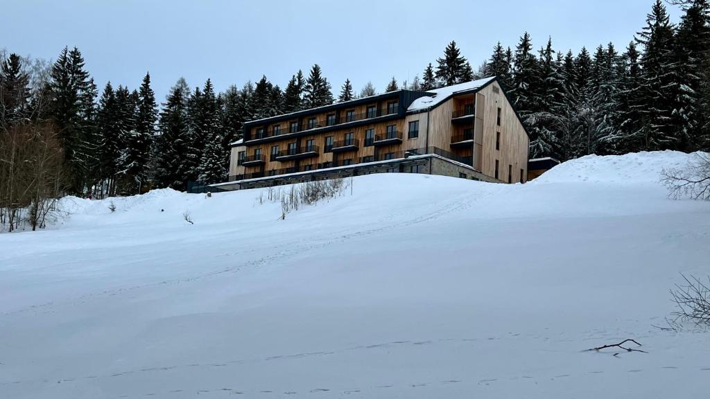 a building on top of a snow covered field at Apartmán s terasou Benecko in Benecko