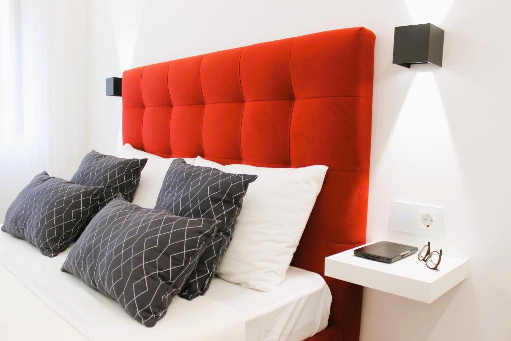 uma cama com uma cabeceira acolchoada e almofadas vermelhas em G 0.8 - G.oogle Nest Smart House em Braga