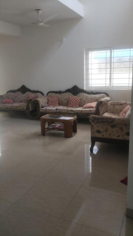 a living room with two couches and a coffee table at Gardenia Groove Villa, Ramky Discovery City in Maisaram