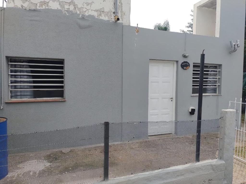 una valla frente a un edificio blanco con una puerta en Departamento Jorge en Marcos Juárez