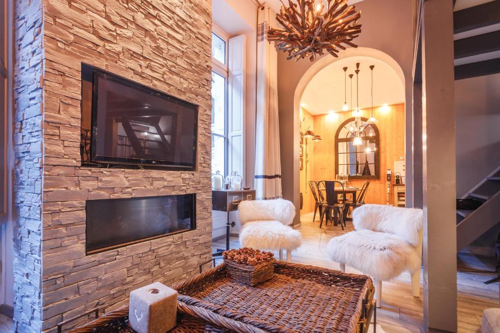 - un salon avec une cheminée en pierre et une télévision dans l'établissement L'Écrin - 76m2 - 8P - Centre Ville Cauterets, à Cauterets