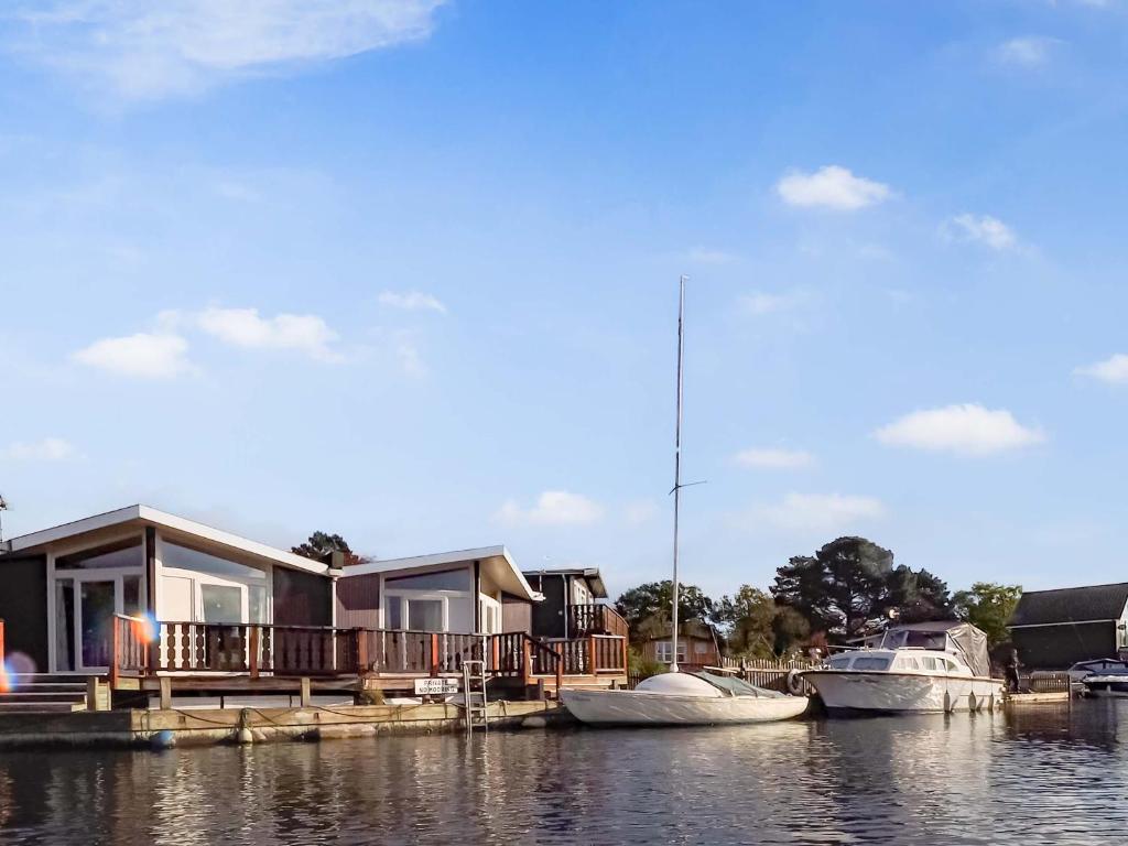 a house on a dock with boats in the water at Ripples in Horning