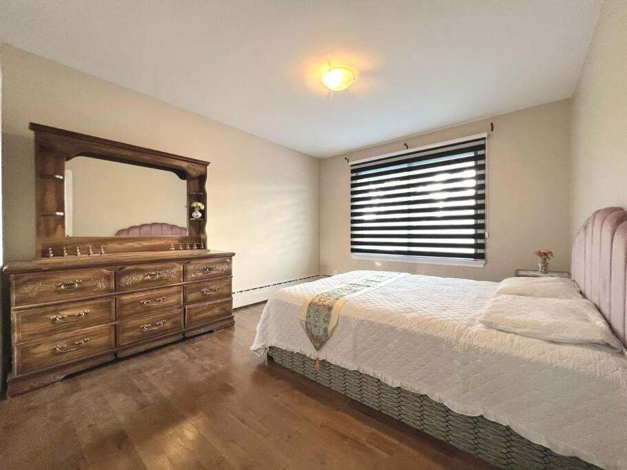 拉瓦尔Comfortable entire 3BDR Apt in Laval Montreal的卧室里有一张床和一个带镜子的梳妆台