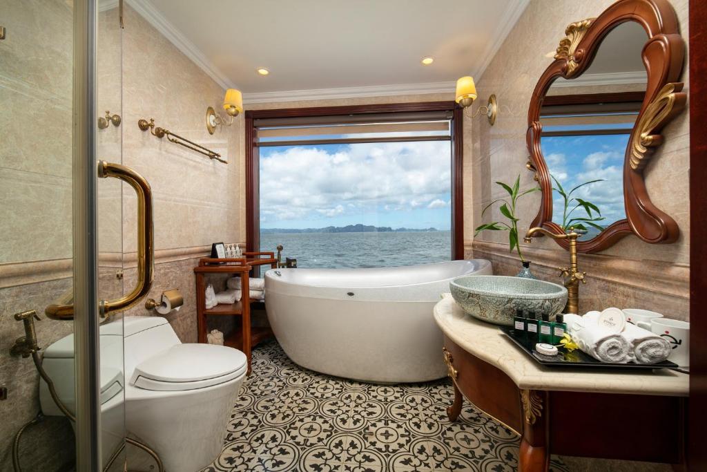 a bathroom with a tub and a toilet and a sink at Emperor Cruises Legacy Ha Long in Ha Long