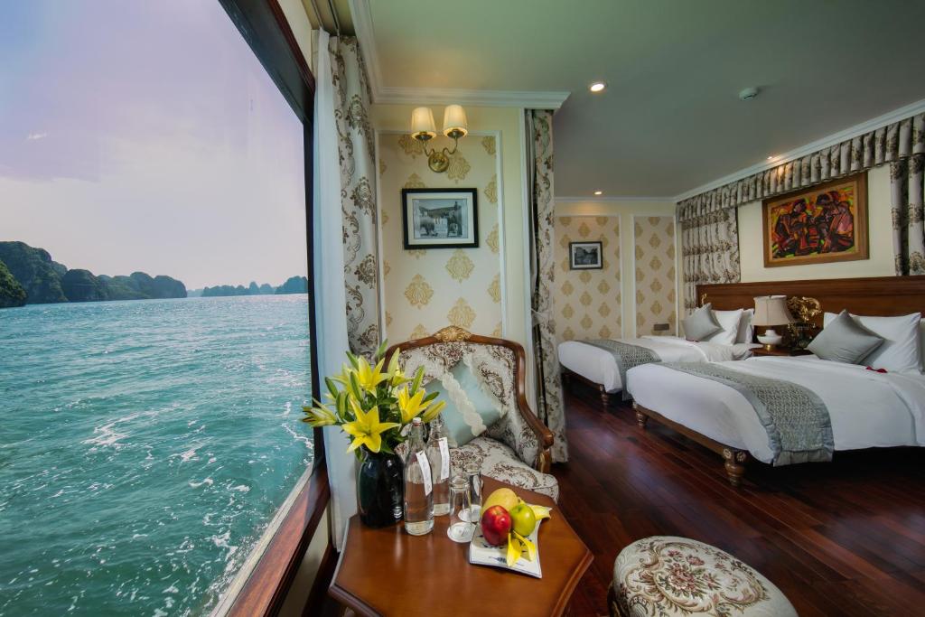 a bedroom with two beds and a view of the water at Emperor Cruises Legacy Ha Long in Ha Long