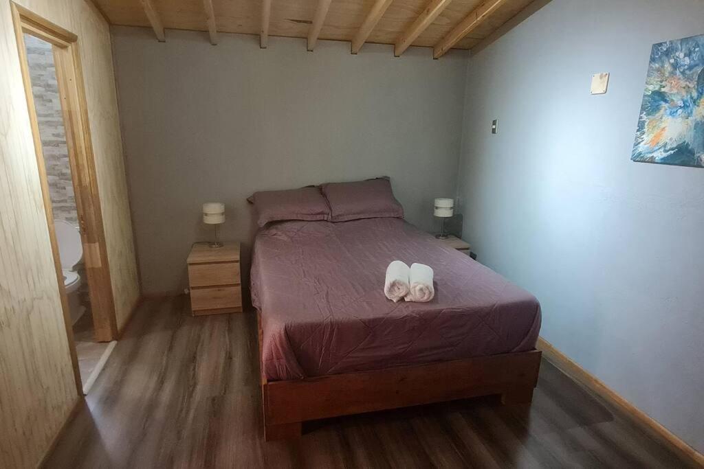 Un dormitorio con una cama con dos zapatos blancos. en Departamento Los Leones en Villa O'higgins con WIFI, en Villa O'Higgins