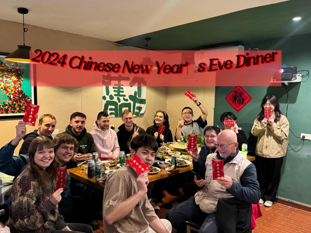 een groep mensen die aan een tafel zitten met rode kaarten bij Guilin Cyan Box Guest House in Guilin