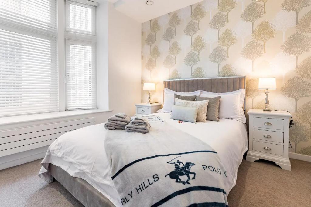 um quarto com uma cama grande com lençóis brancos e almofadas em Deansgate Luxury Apartments em Manchester