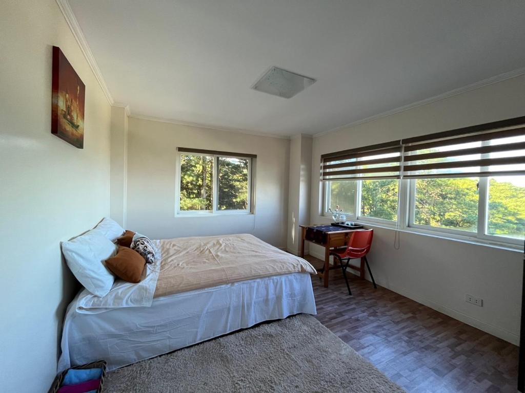 1 dormitorio con 1 cama, escritorio y 2 ventanas en Baguio BELL Staycation, en Baguio