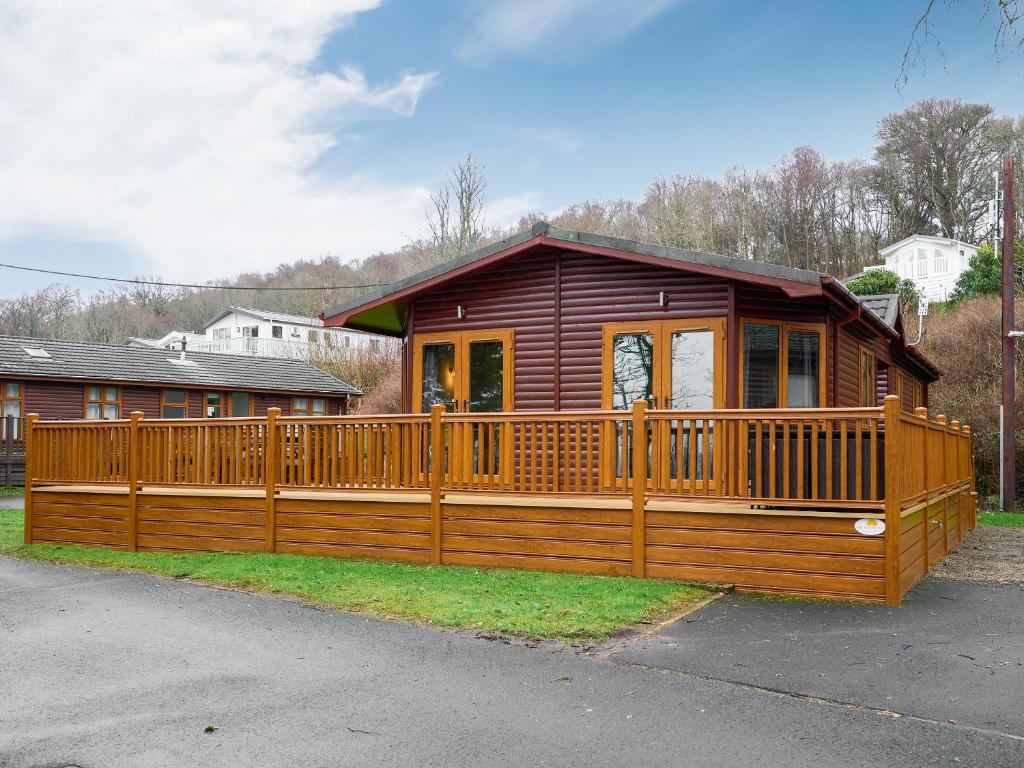 a large wooden cabin with a large deck at Cabin Retreat in Skelmorlie