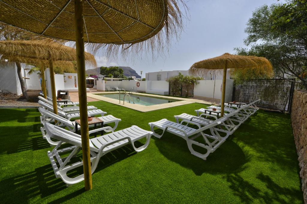 un gruppo di sedie a sdraio e ombrelloni accanto alla piscina di Hotel Calachica Las Negras a Las Negras