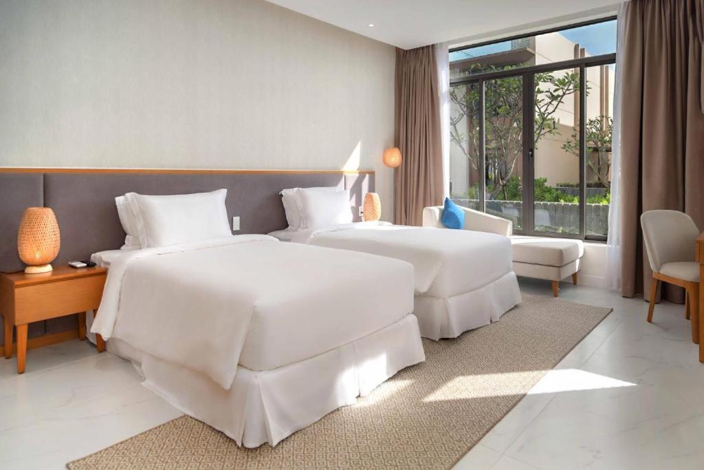 une chambre d'hôtel avec deux lits et une fenêtre dans l'établissement Apartment in Wyndham Garden Cam Ranh, à Nha Trang