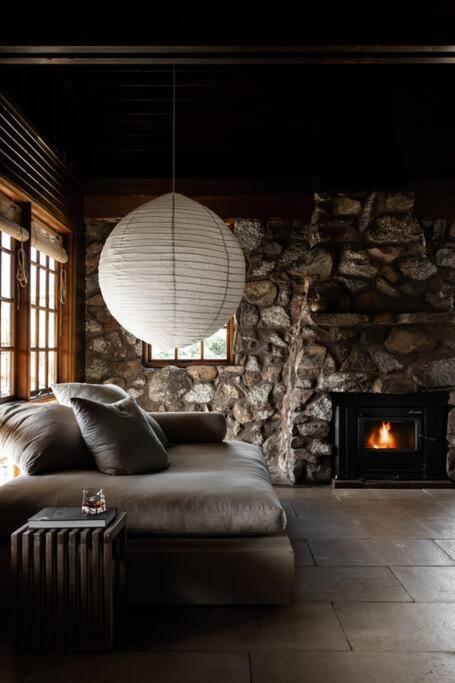 a living room with a couch and a stone wall at SABI Award Winning Designer Cabin in Binalong Bay