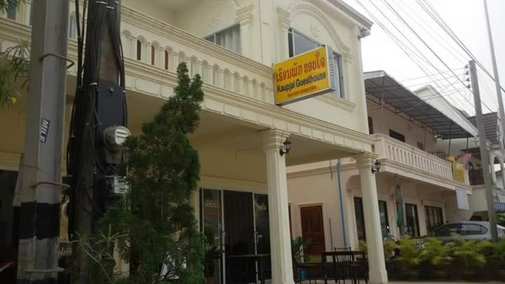 a large white building with a yellow sign on it at KhopChai Guesthouse in Ban Houayxay