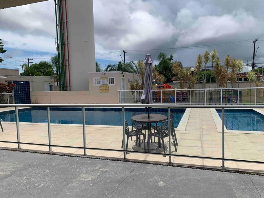 einen Tisch mit einem Sonnenschirm neben einem Pool in der Unterkunft Ap proximo ao Aeroporto e ao Shopping Pátio Maceió in Maceió