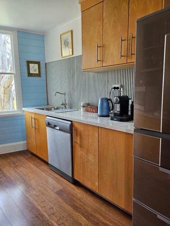 a kitchen with wooden cabinets and a stainless steel refrigerator at Stay at Tilba in Central Tilba