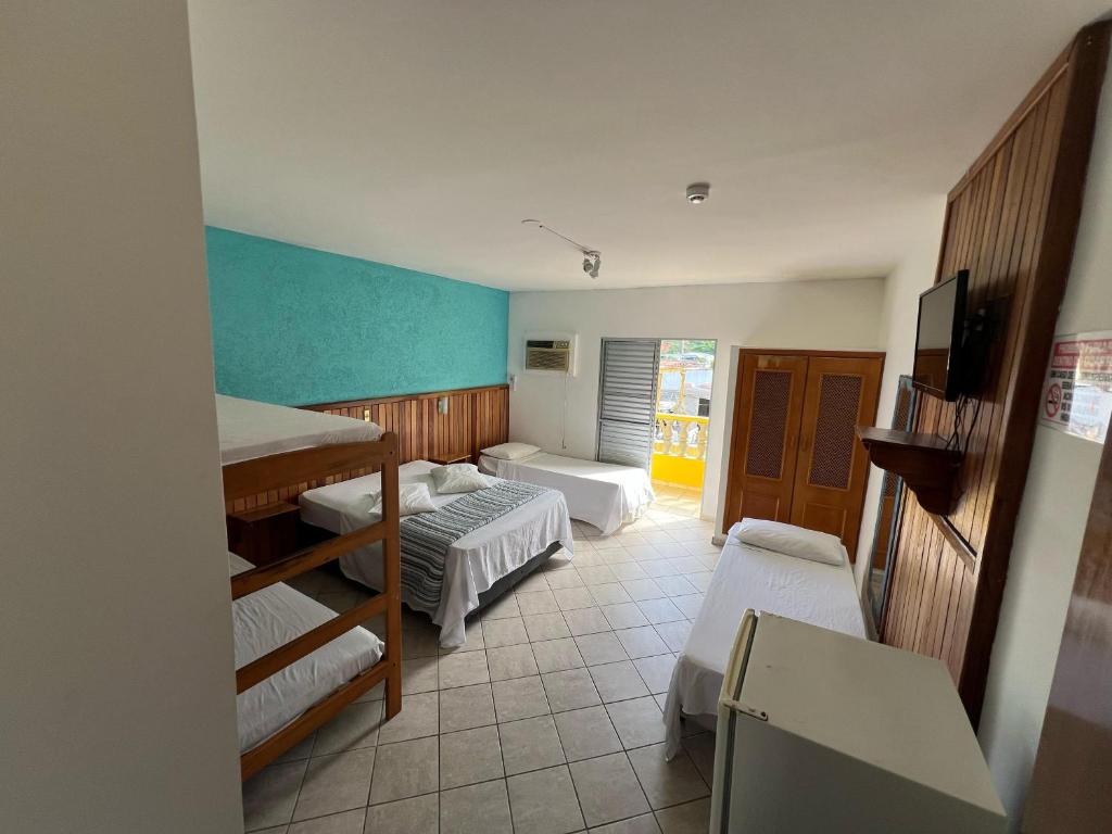 a small room with two beds and a tv at Pousada Martin de Sá in Caraguatatuba