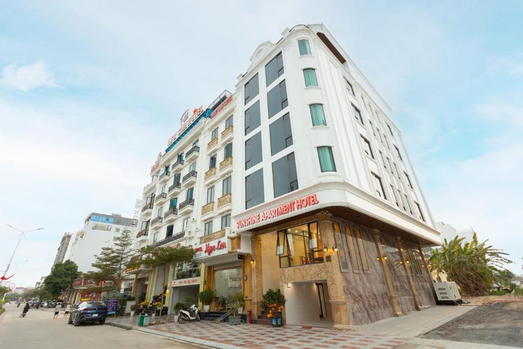 un edificio blanco alto en una calle de la ciudad en Sunshine Apartment Hotel en Móng Cái