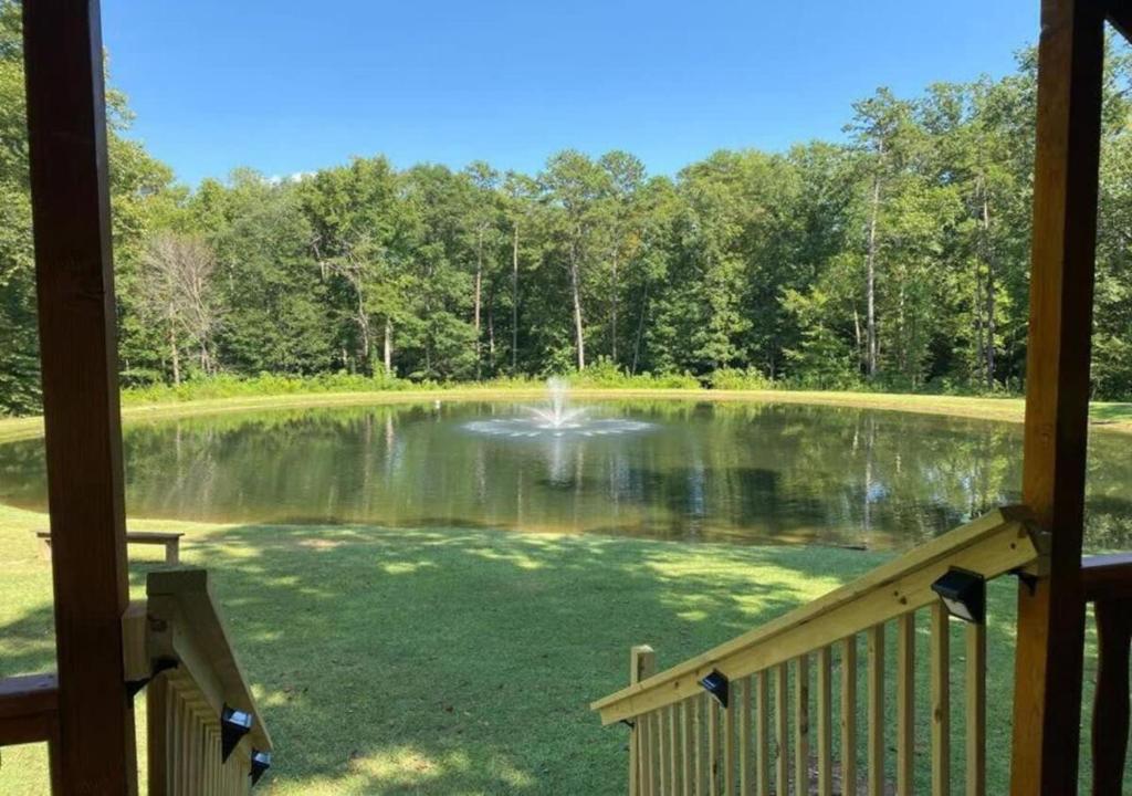 a view of a pond from the porch of a cabin at Serene 1BR Cabin near NC Z00 with Loft & Waterview in Asheboro