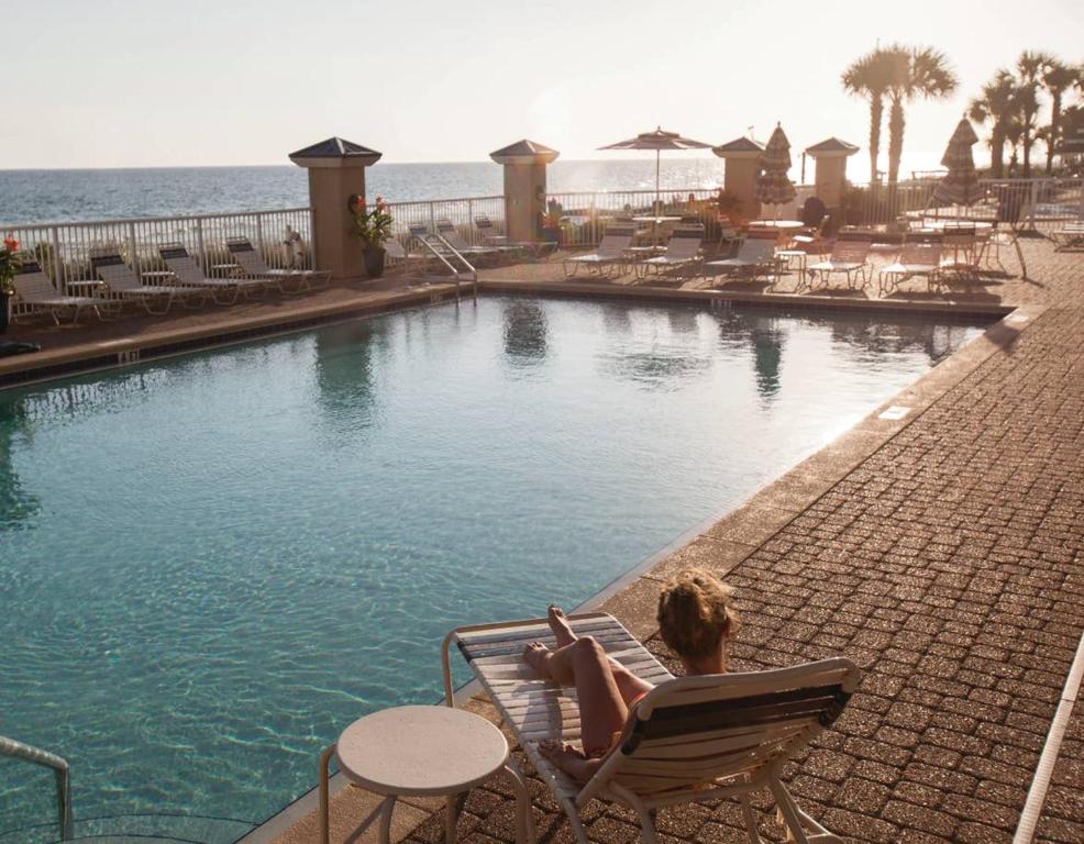 una mujer sentada en una silla junto a una piscina en Holiday Inn Club Vacations Panama City Beach Resort en Panama City Beach