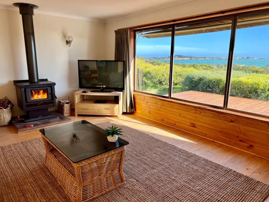 a living room with a fireplace and a television at C4 Miles Beach Shack in Robe