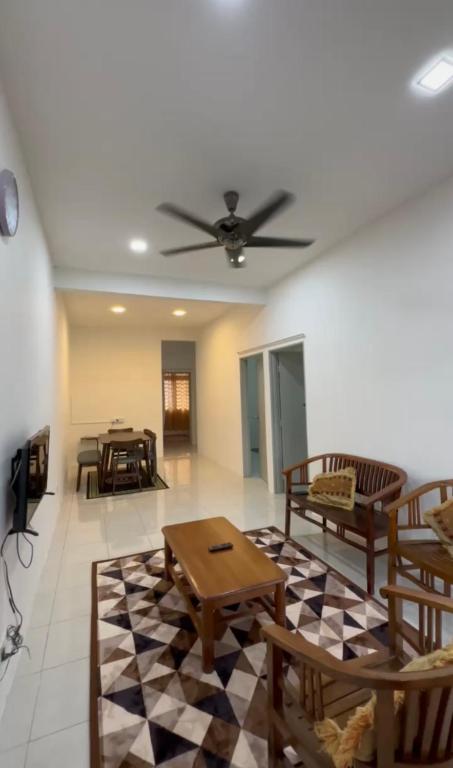 a living room with a ceiling fan and a table at Muqryy Homestay in Marang